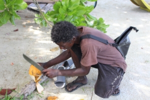Local on beach preparing coconut